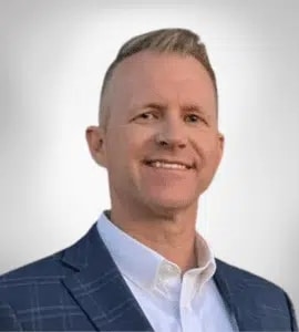 Professional headshot of a smiling man in a blue suit jacket and white shirt.